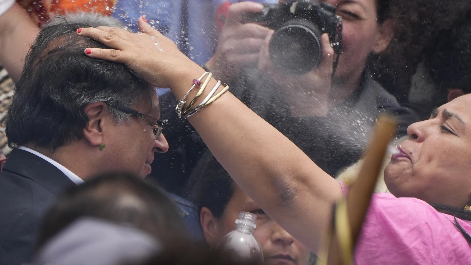 Una mujer indígena escupe agua sobre la cabeza del presidente electo Gustavo Petro, durante una ceremonia de investidura "popular y espiritual" presidida por grupos indígenas locales y activistas feministas, en Bogotá