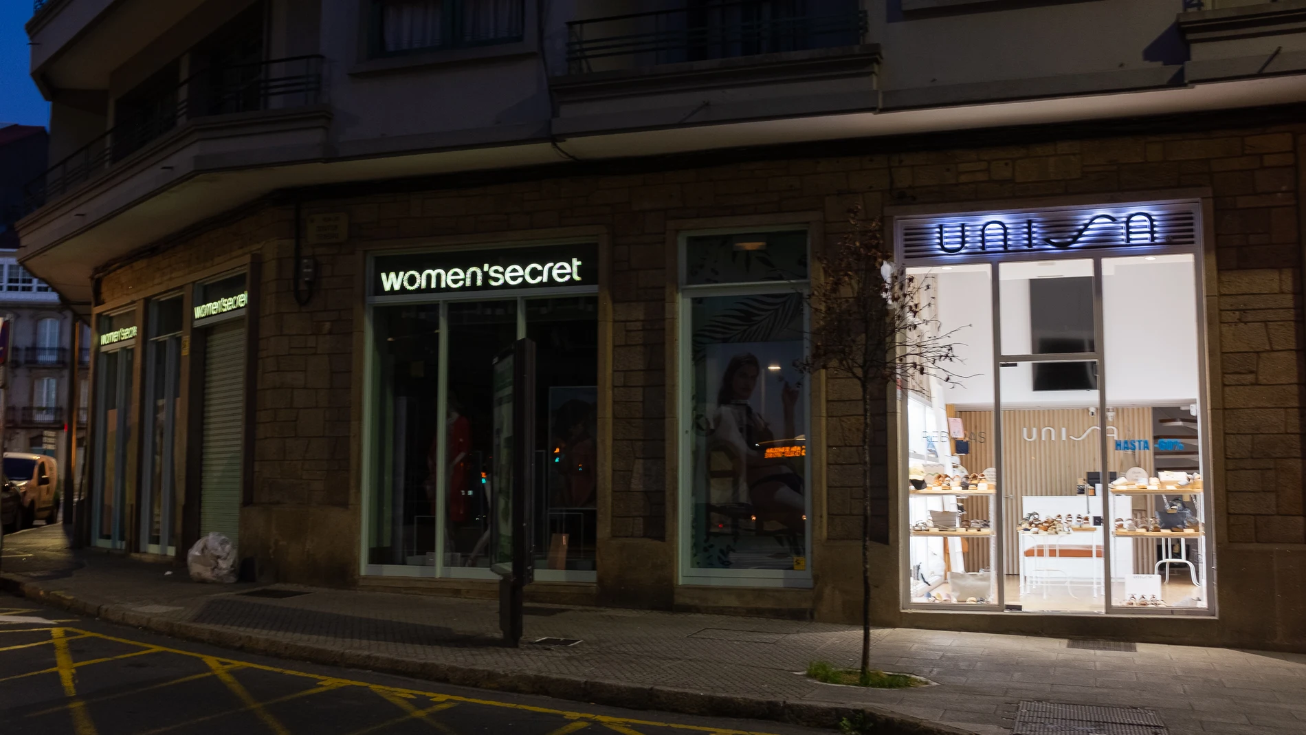 Un comercio con la luz apagada en su interior al lado de otro con la luz encendida, en Santiago de Compostela