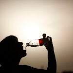 Una turista bebe agua para aliviar el intenso calor mientras pasea por el puente romano de Córdoba d