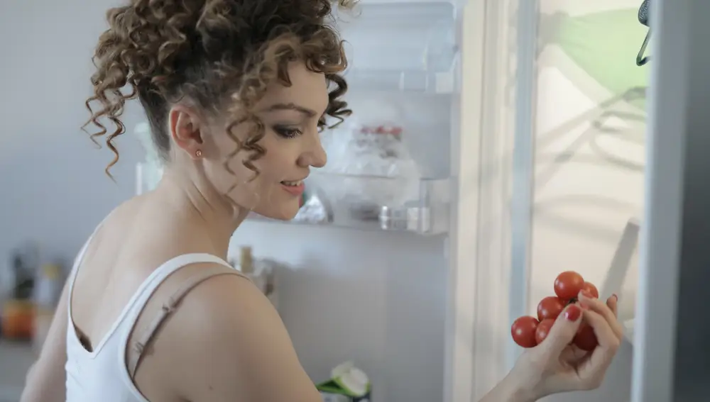 Mujer sacando tomates de la nevera
