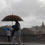 Dos personas caminan bajo sus paraguas en Sevilla 