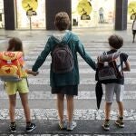 Una madre lleva a sus dos hijos al colegio