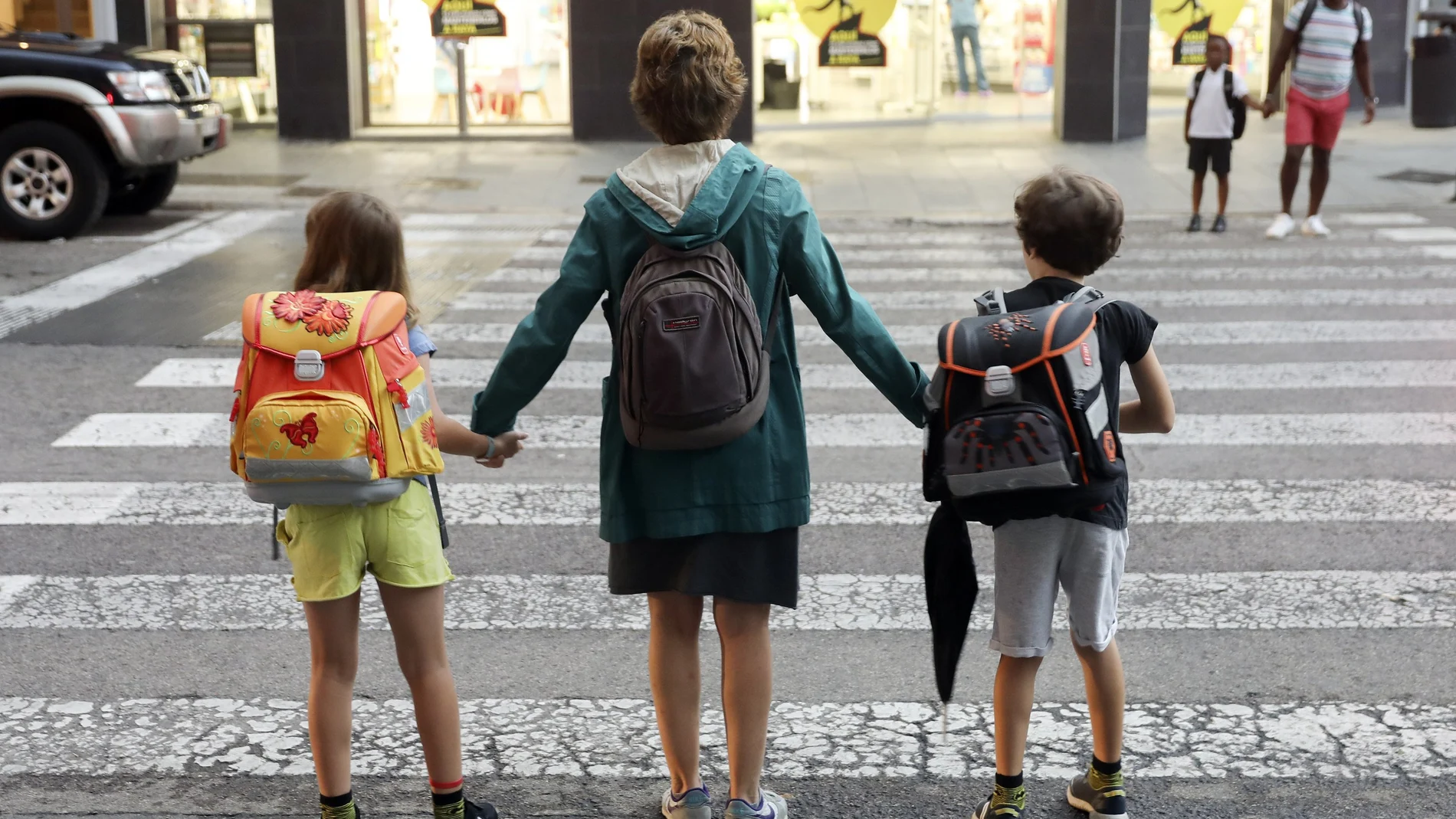 Una madre lleva a sus dos hijos al colegio