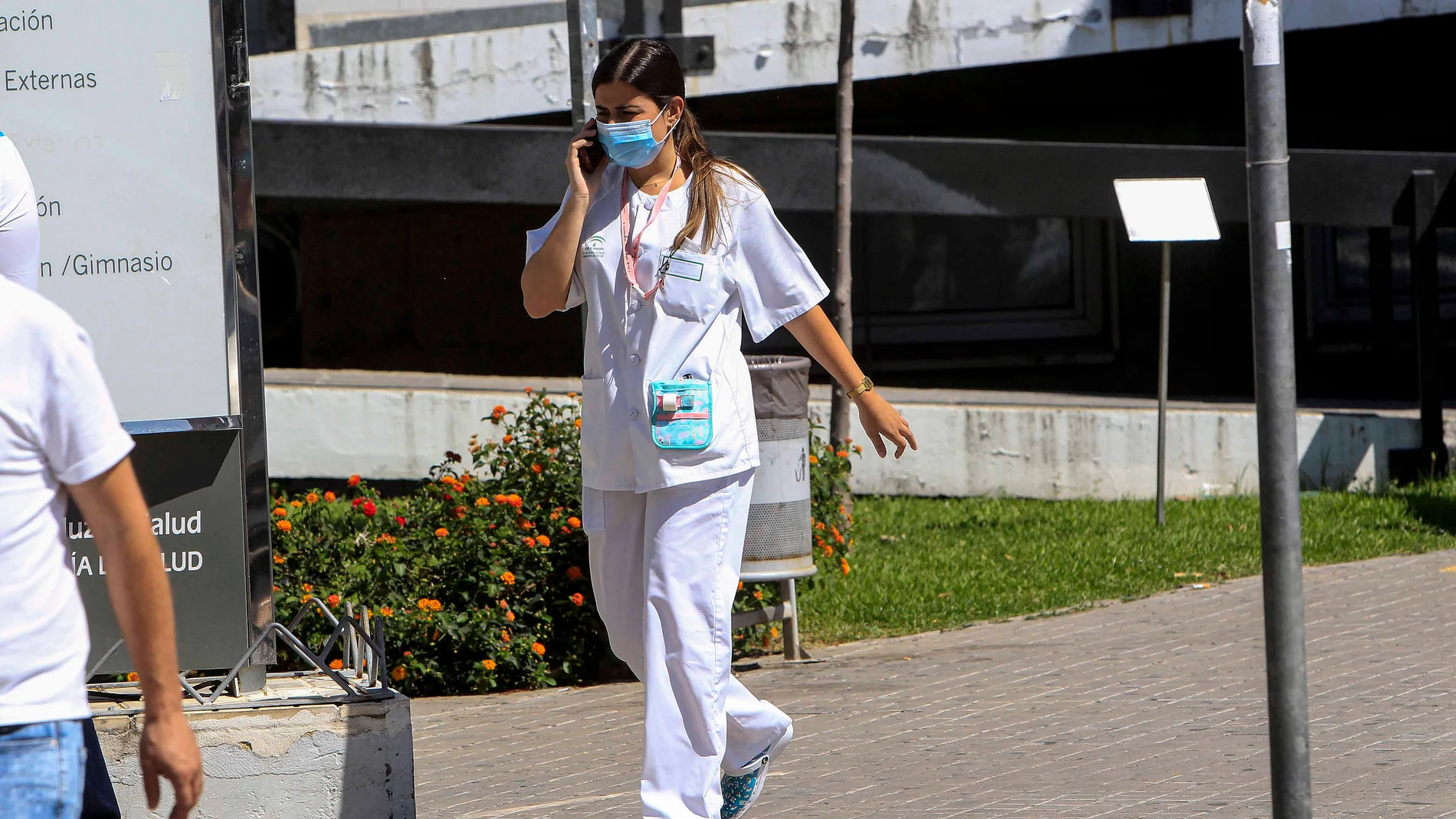 Una sanitaria habla por el móvil con mascarilla en el Hospital Virgen Macarena de Sevilla
