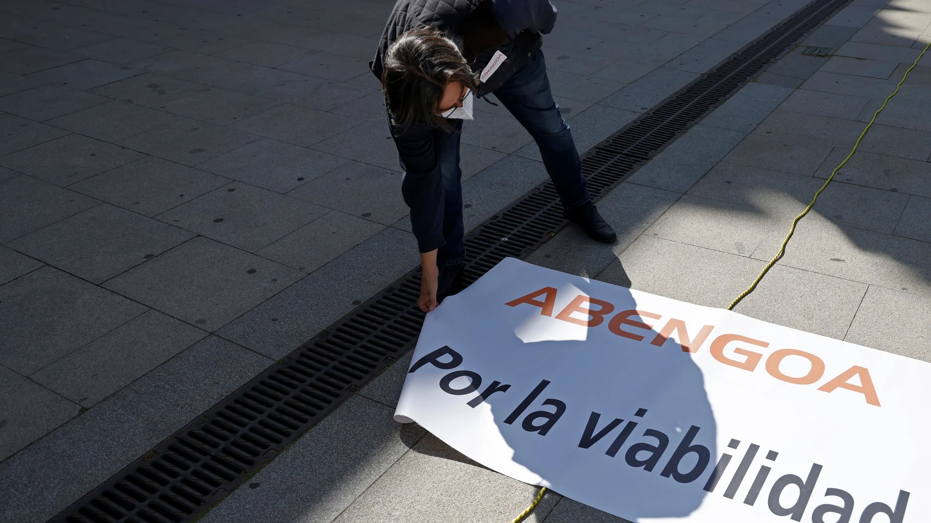 Un trabajador de Abengoa despliega un cartel donde se pide por la viabilidad de la empresa