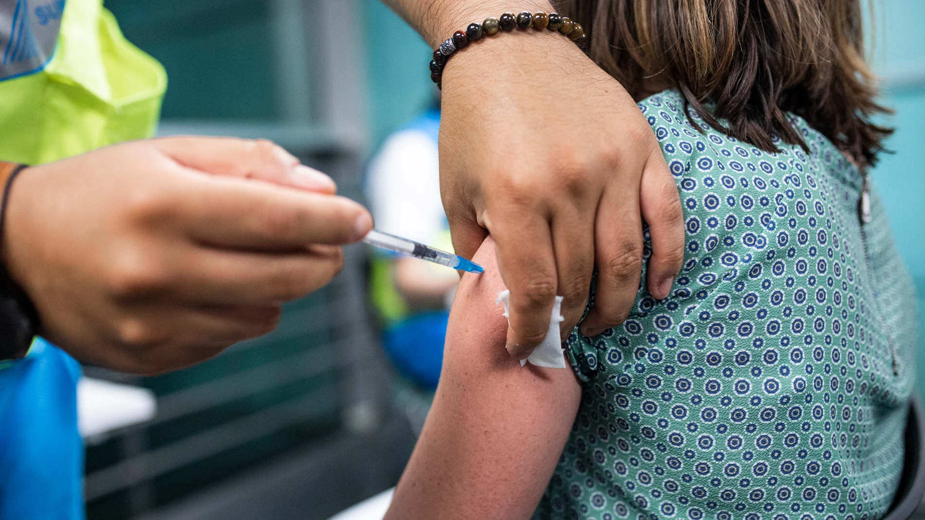 Un sanitario administra una dosis de la vacuna de Pfizer a una mujer en el Wizink Center
