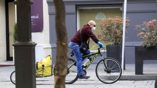 Un hombre circula en bicicleta por Sevilla con mascarilla por el Covid-19