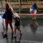 Varias personas se protegen de la lluvia en el distrito madrileño de Villaverde