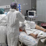 Dos sanitarios alrededor de un paciente ingresado en un hospital de Madrid