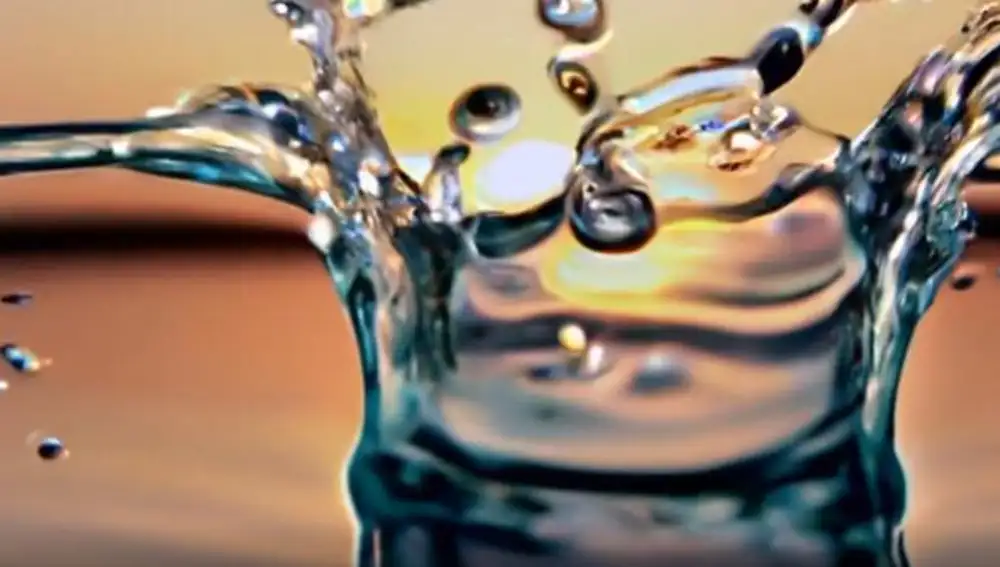 Gota cayendo sobre agua con el atardecer de fondo.