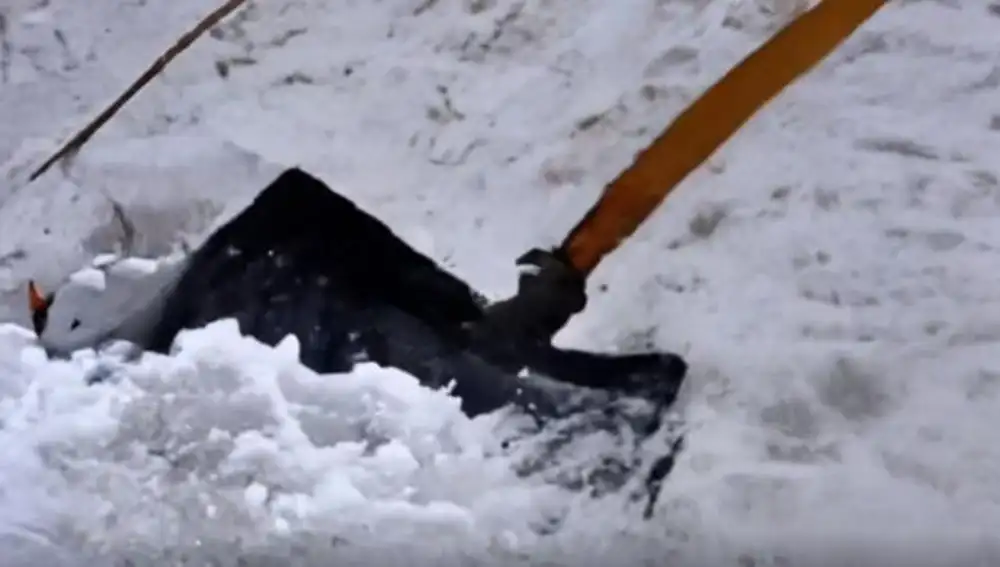 Apartando nieve con una pala.