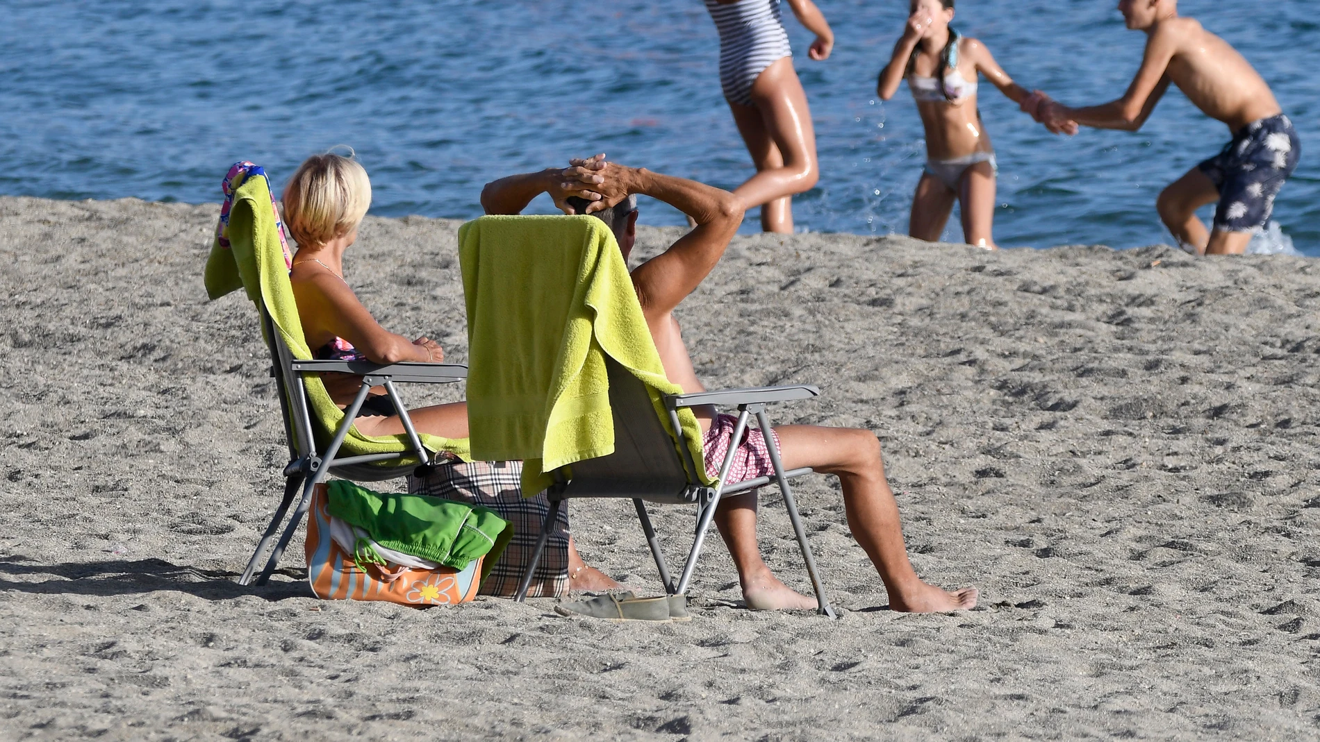 Unas personas disfrutan del buen tiempo en la playa de Aguadulce en Roquetas de Mar (Almería)