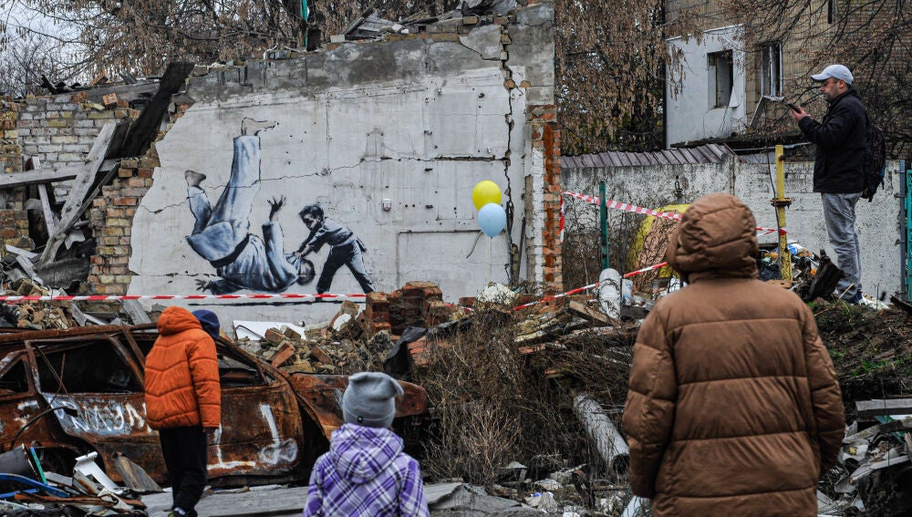 La gente observa los grafitis realizados con el estilo característico del artista callejero británico Banksy