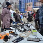 Unos vecinos cargan sus teléfonos móviles con un generador en una calle de la ciudad de Jersón