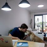 El joven madrileño Alejandro Rodríguez, junto a su perra Gema, vive en Benalmádena (Málaga), donde trabaja de forma telemática para una empresa con sede en Silicon Valley, en California. EFE/Jorge Zapata.