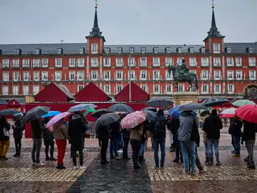 Un grupo de turistas se protegen de la lluvia en la Plaza Mayor de Madrid Un grupo de turistas se protegen de la lluvia en la Plaza Mayor de Madrid