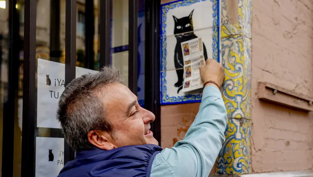 Una persona pone el décimo recién comprado en el azulejo que representa a el gato negro en la administración de loterías ‘El Gato Negro’ situada en la Av de la Constitución para comprar la Lotería de Navidad a 07 de diciembre del 2022 en Sevilla (Andalucía, España). 07 DICIEMBRE 2022 Eduardo Briones / Europa Press 07/12/2022