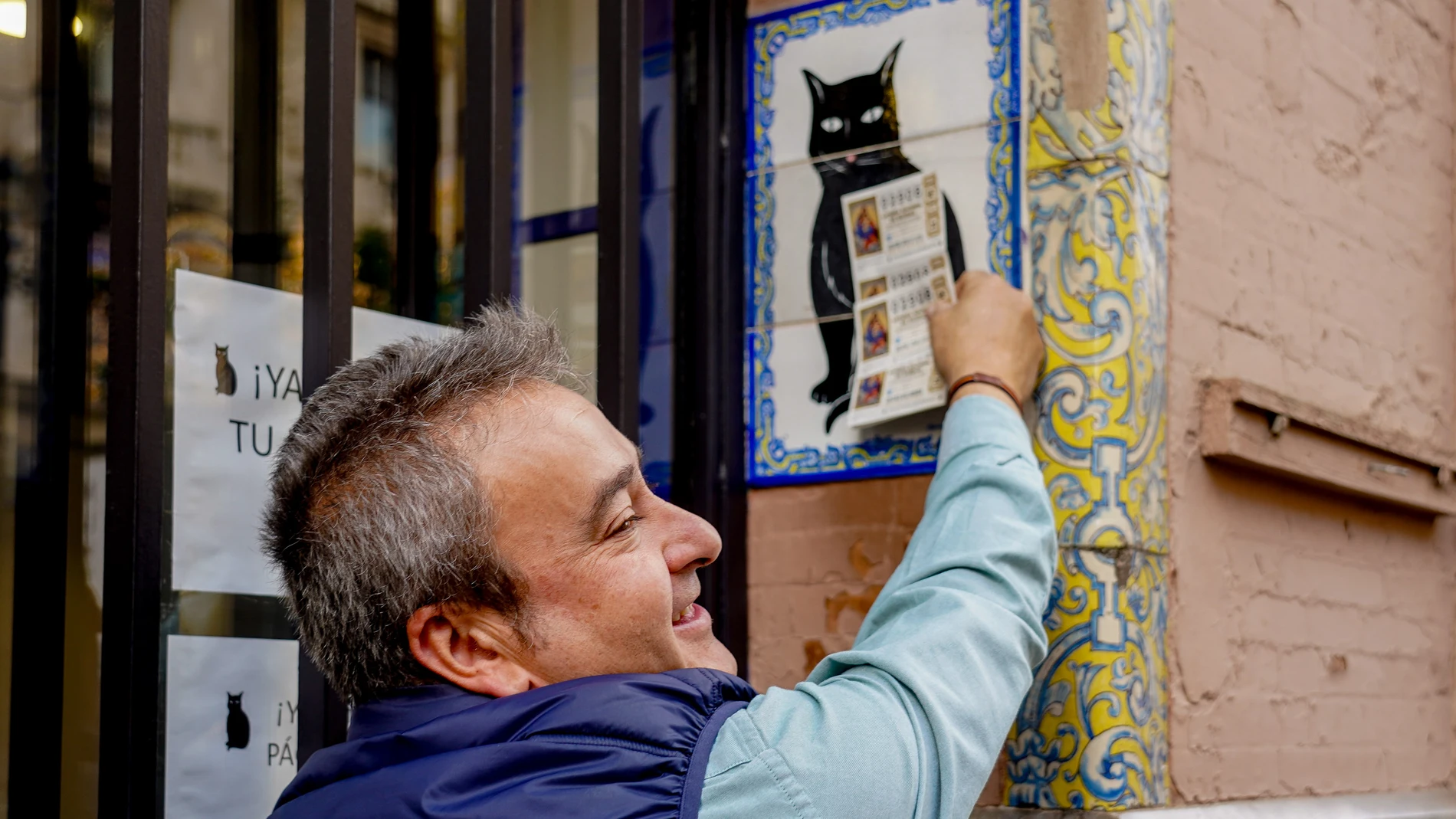 Una persona pone el décimo recién comprado en el azulejo que representa a el gato negro en la administración de loterías ‘El Gato Negro’ situada en la Av de la Constitución para comprar la Lotería de Navidad a 07 de diciembre del 2022 en Sevilla (Andalucía, España). 07 DICIEMBRE 2022 Eduardo Briones / Europa Press 07/12/2022