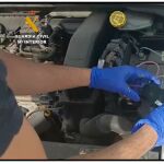 Un agente examina el motor del coche de la mujer para buscar el dispositivo de seguimiento