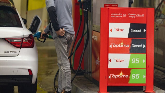 Una persona echa gasolina del surtidor de una gasolinera
