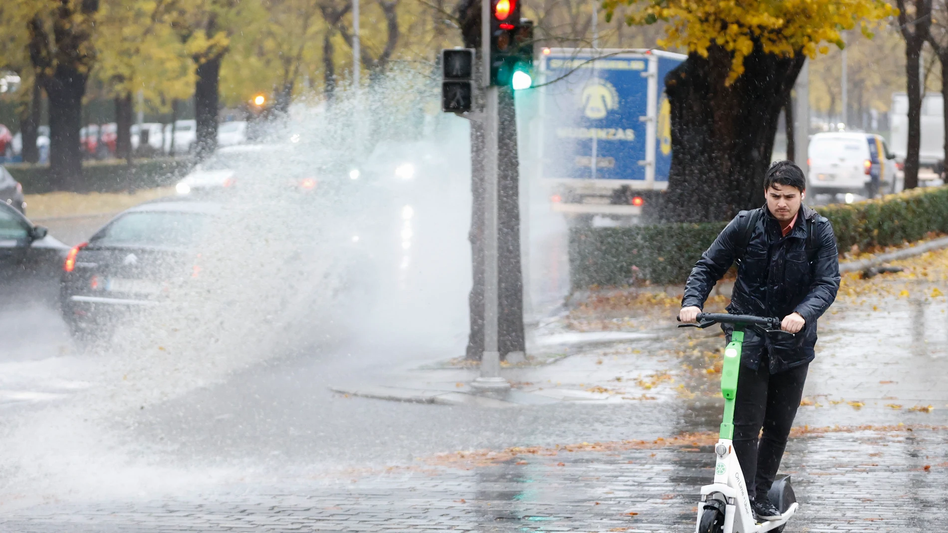 Un hombre usa un patinete eléctrico bajo la lluvia en Madrid
