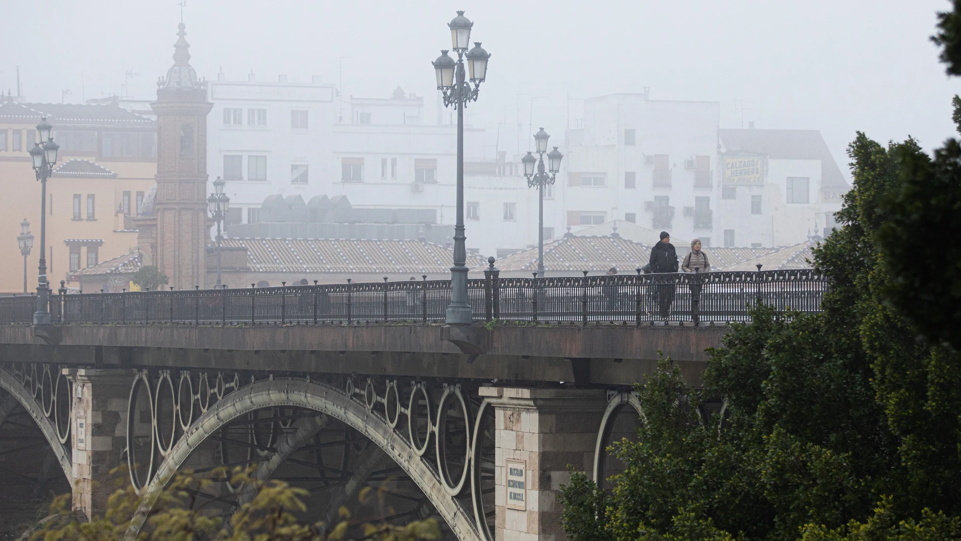 El puente de Isabel II conocido como el Puente de Triana, cubierto de niebla