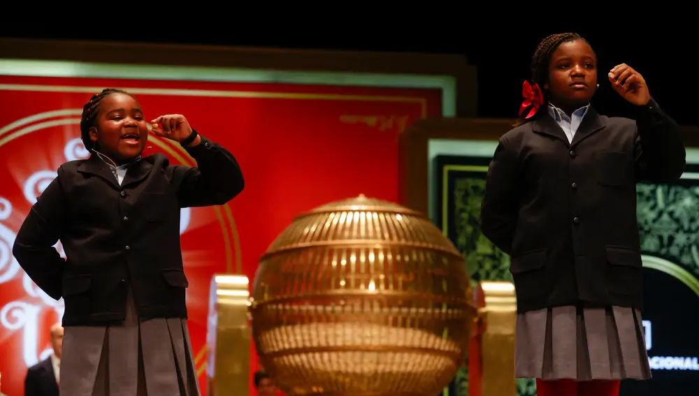Las estudiantes de San Ildefonso Yesica Paola Valencia Gómez (d) y su compañera Ainhoa Rosero Gómez (i) cantan el segundo premio durante el sorteo de El Gordo de Navidad en el Teatro Real en Madrid