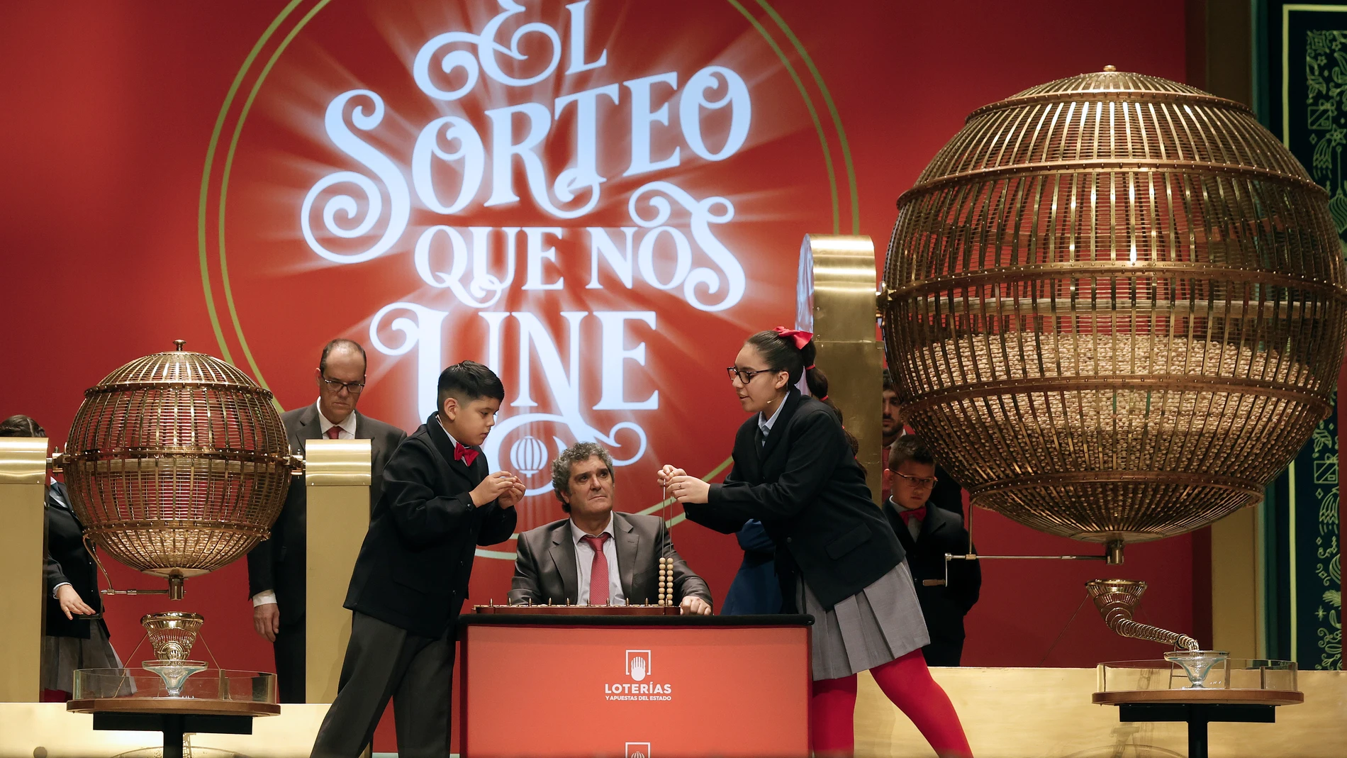 Los estudiantes de San Ildefonso Luis Alcides Paniagua (i) y su compañera Kiara Román Benitez (d) cantan números y premios durante el sorteo de El Gordo de Navidad en el Teatro Real en Madrid, este jueves. EFE/ Javier Lizón