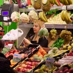 Un dependienta pesa una bolsa con frutas 