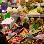 Un dependienta pesa una bolsa con frutas