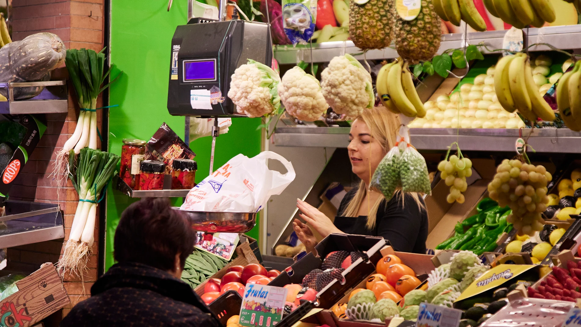 Un dependienta pesa una bolsa con frutas