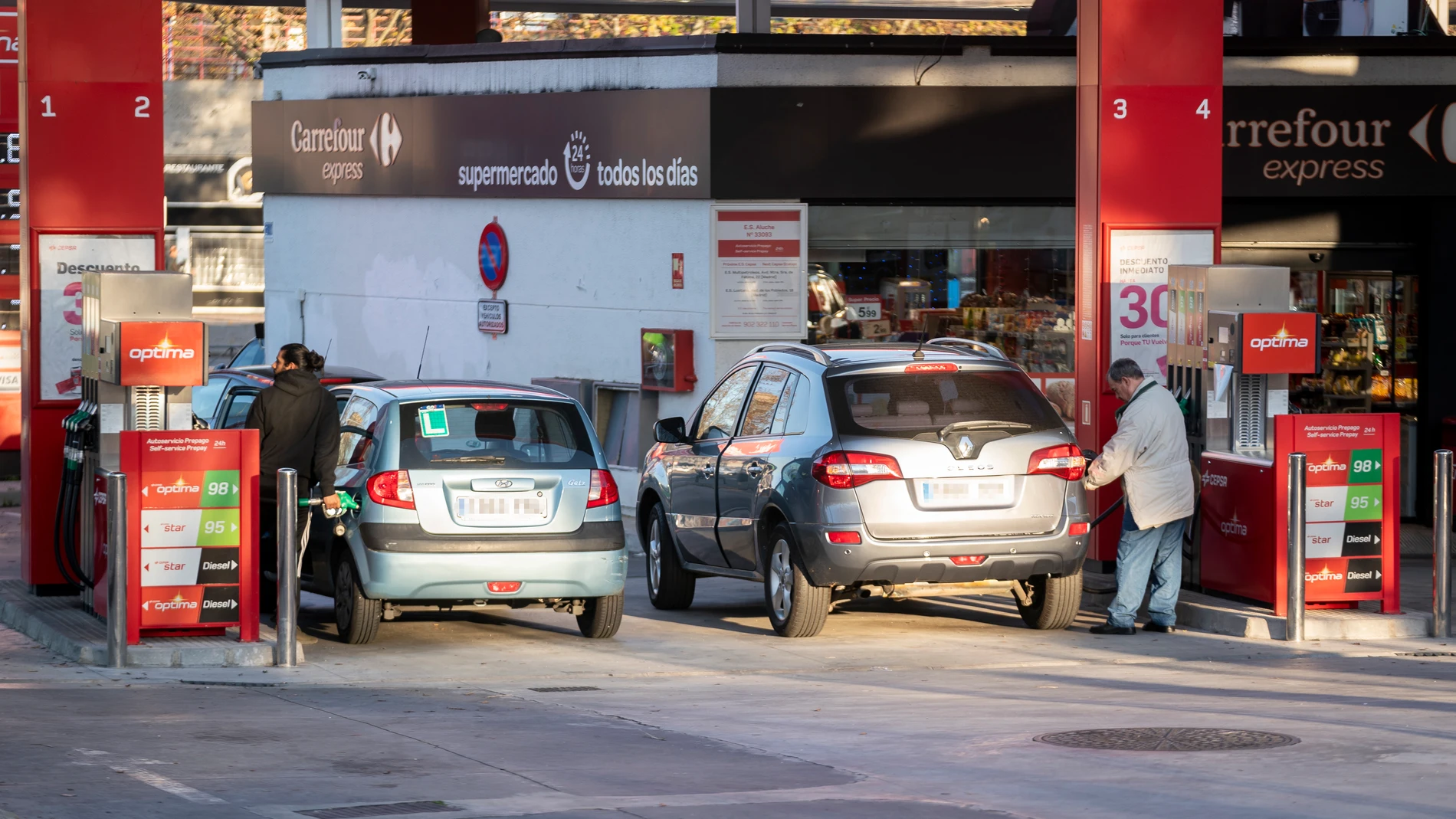 Dos personan repostan combustible en una gasolinera