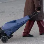 Una mujer mayor sale de un supermercado con un carro de la compra