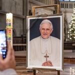 Un hombre toma una fotografía frente a un retrato de Benedicto XVI en la catedral de San Pedro en Regensburg, Alemania