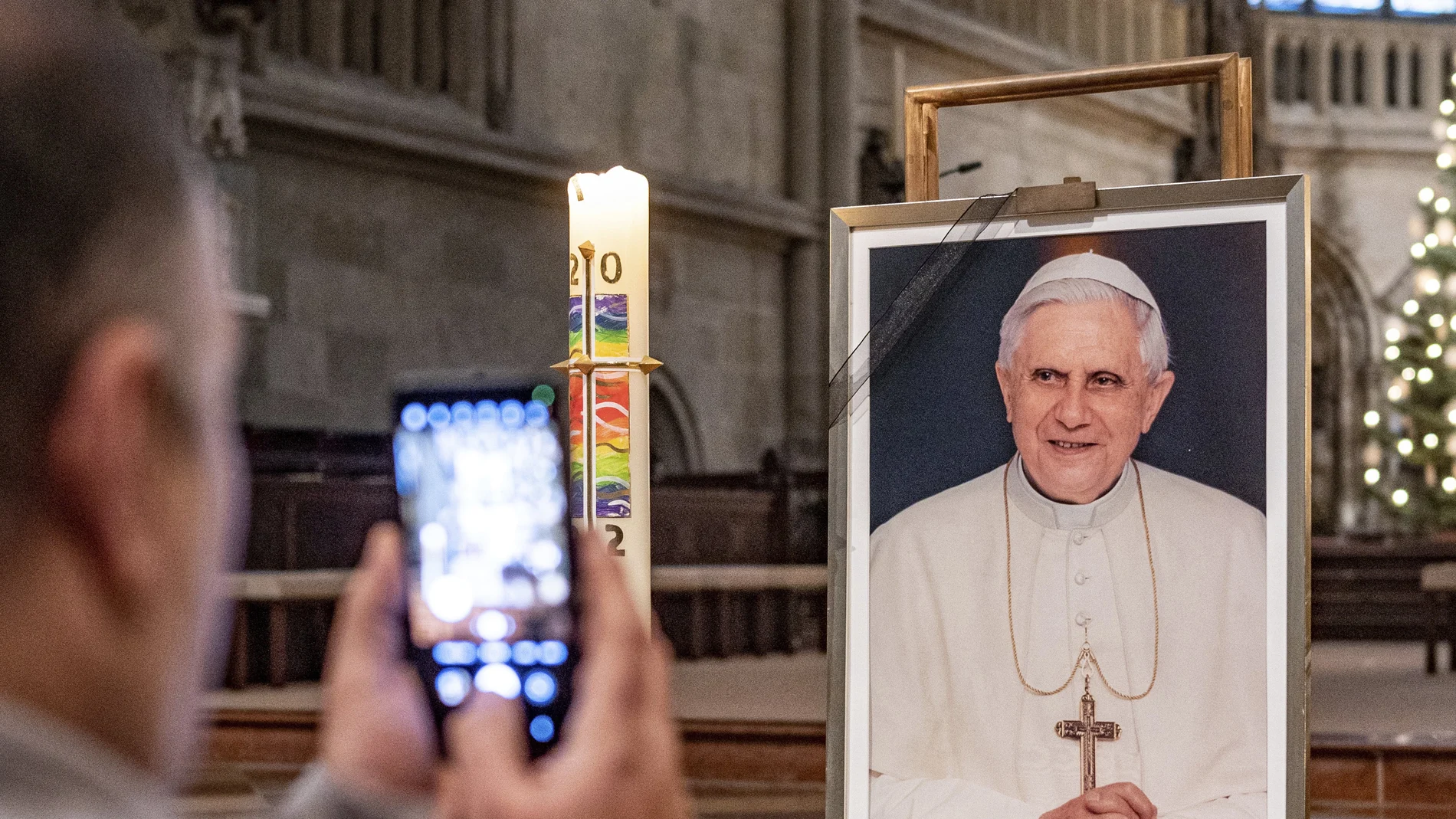 Un hombre toma una fotografía frente a un retrato de Benedicto XVI en la catedral de San Pedro en Regensburg, Alemania