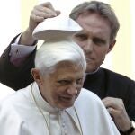 El reverendo Georg Gaenswein, quien fuera secretario de Benedicto XVI, le ayuda a ponerse el solideo en la audiencia general en San Pedro en octubre de 2006