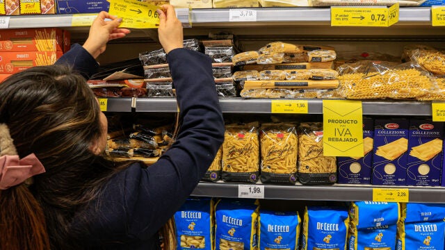 Una empleada de un supermercado coloca los carteles 