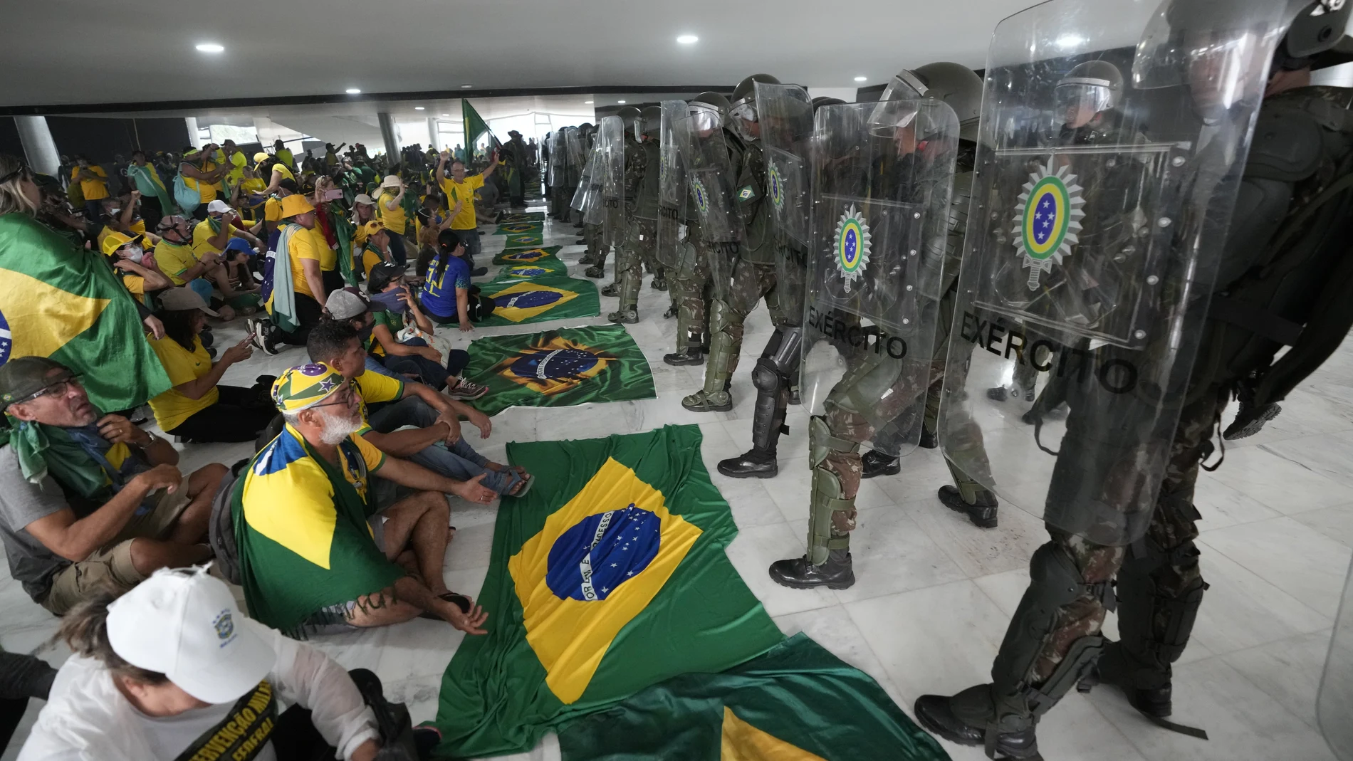Manifestantes, partidarios del expresidente de Brasil Jair Bolsonaro, se sientan frente a la policía después de dentro del Palacio de Planalto después de irrumpir en él, en Brasilia