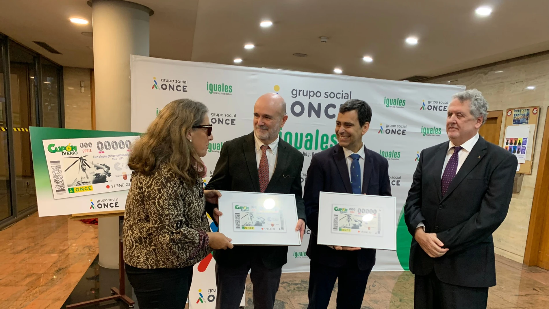 El consejero de Fomento, José Ramón Díez de Revenga, junto a los representantes de la Delegación territorial de la ONCE en la Región de Murcia, y miembros de la familia de Juan de la Cierva, durante la presentación del cupón conmemorativo por el centenario del primer vuelo oficial del autogiro de Juan de la Cierva.