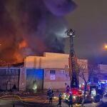 fectivos del cuerpo de bomberos trabajan en las labores de extinción del incendio que ha destruido una nave industrial dedicada a la repostería situada en el Polígono Cobo Calleja de Fuenlabrada