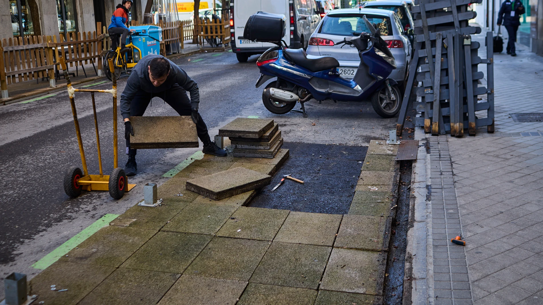 Trabajadores retiran una terraza situada en una de las bandas de estacionamiento regulado en una vía aledaña a la calle Ponzano de Madrid