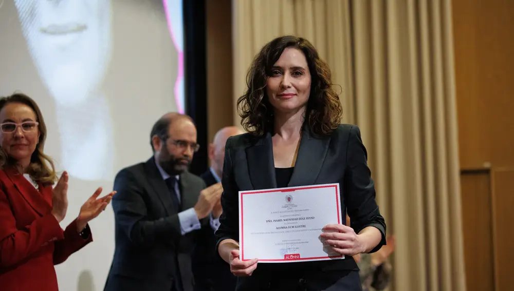 La presidenta de la Comunidad de Madrid, Isabel Díaz Ayuso, posa tras recibir la distinción de Alumna Ilustre de la Universidad Complutense de Madrid