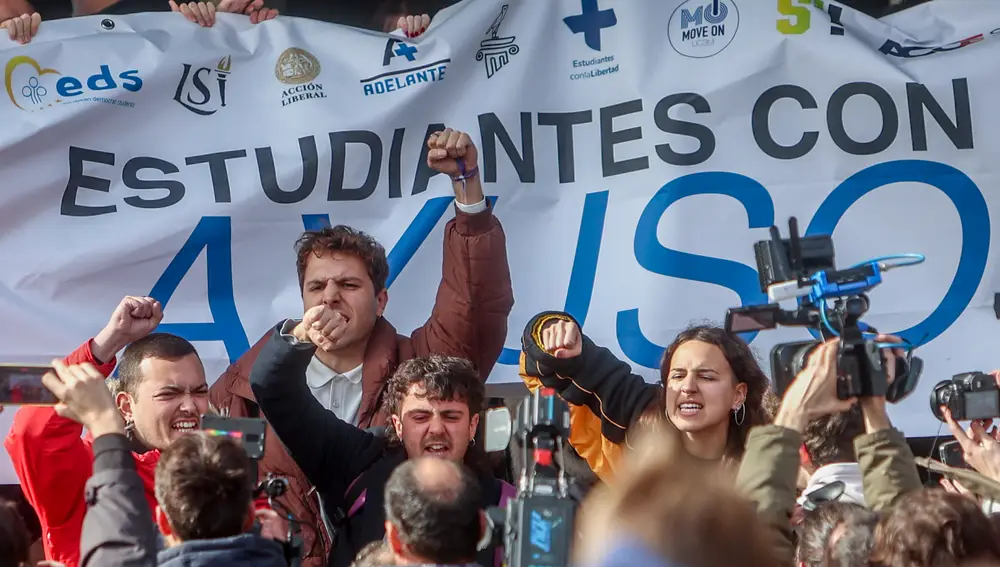 Varios estudiantes intentan tapar una pancarta a favor de la presidenta de la Comunidad de Madrid