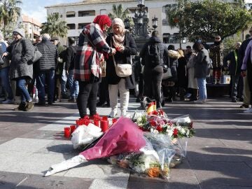 Dos mujeres colocan una vela en el sitio donde asesinaron al sacrist&aacute;n Diego Valencia de la iglesia de la Palma en Algeciras (C&aacute;diz)