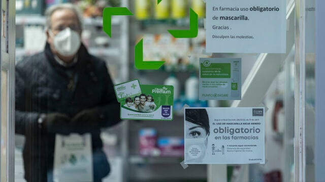 Un hombre sale de una oficina de farmacia con mascarilla
