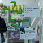 Un hombre sale de una oficina de farmacia con mascarilla