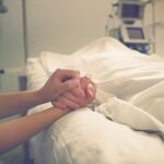 Manos cogidas entre paciente y acompañante en un hospital