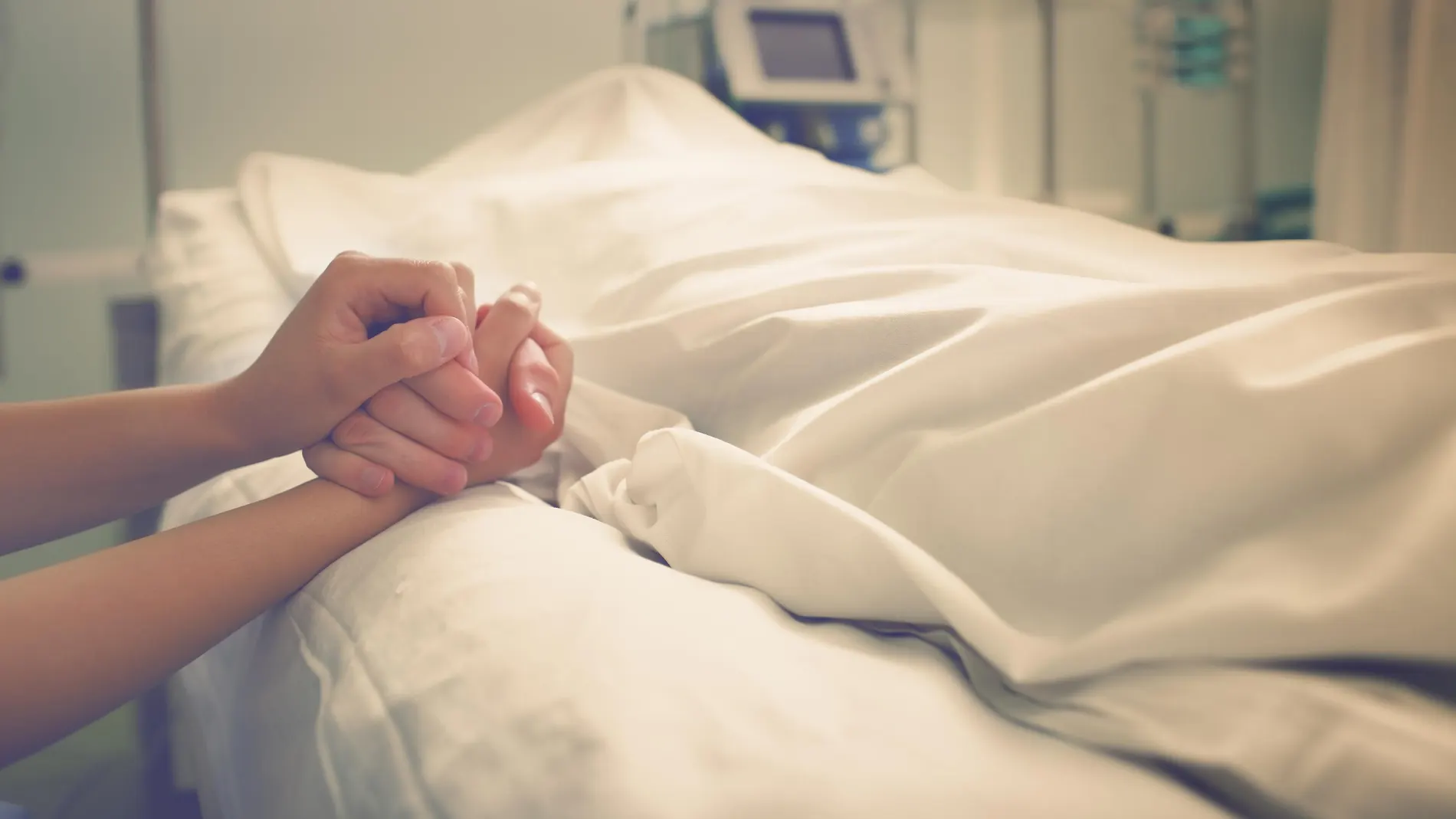 Manos cogidas entre paciente y acompañante en un hospital