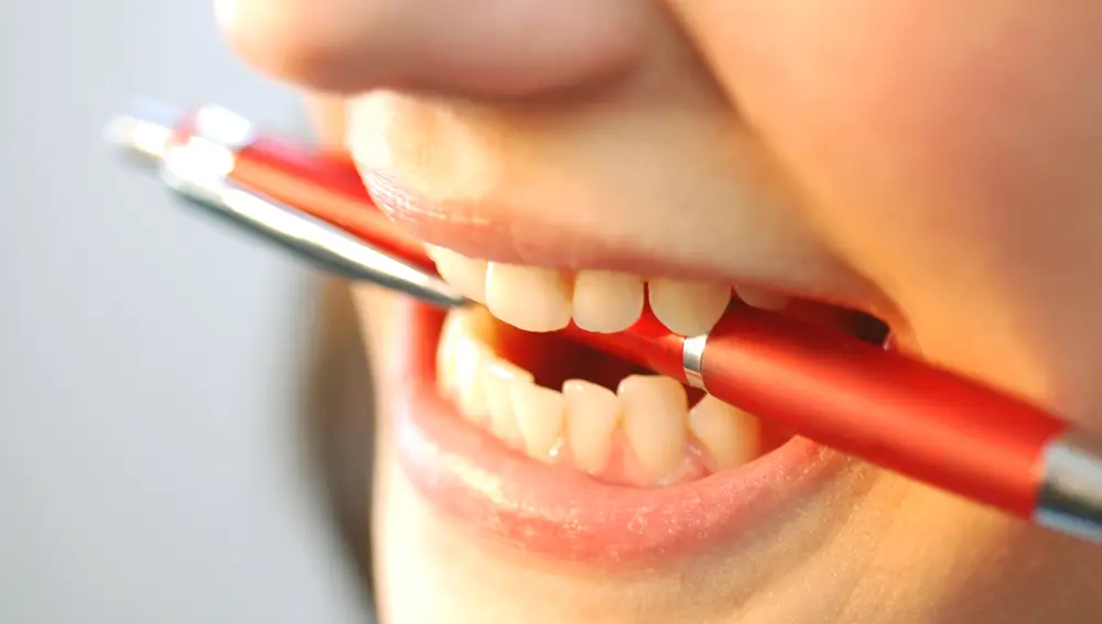Mujer con un boli rojo en la boca