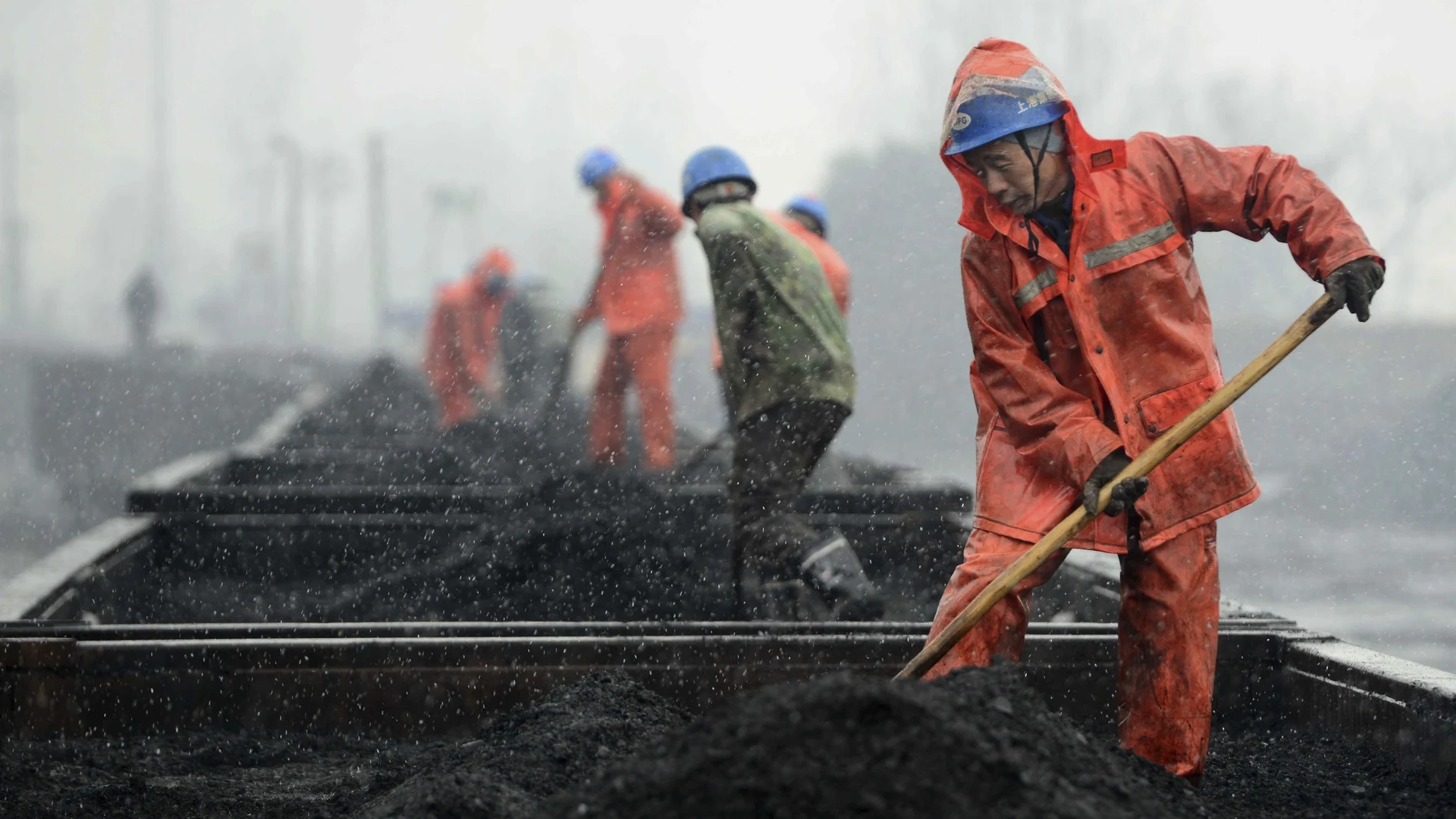 Varios trabajadores bajo la nieve en una estación de tren en China